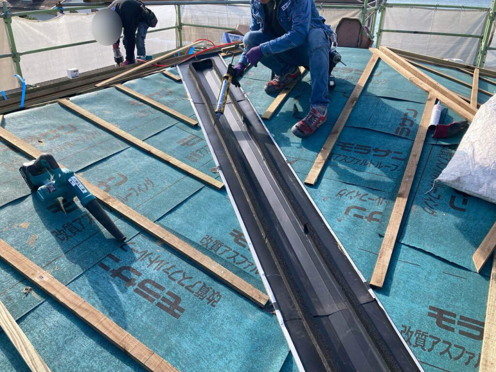 こちらは谷板金の施工の様子。 
雨水が流れる部位のため、隙間にシーリング処理を施して防水性を確保します。 