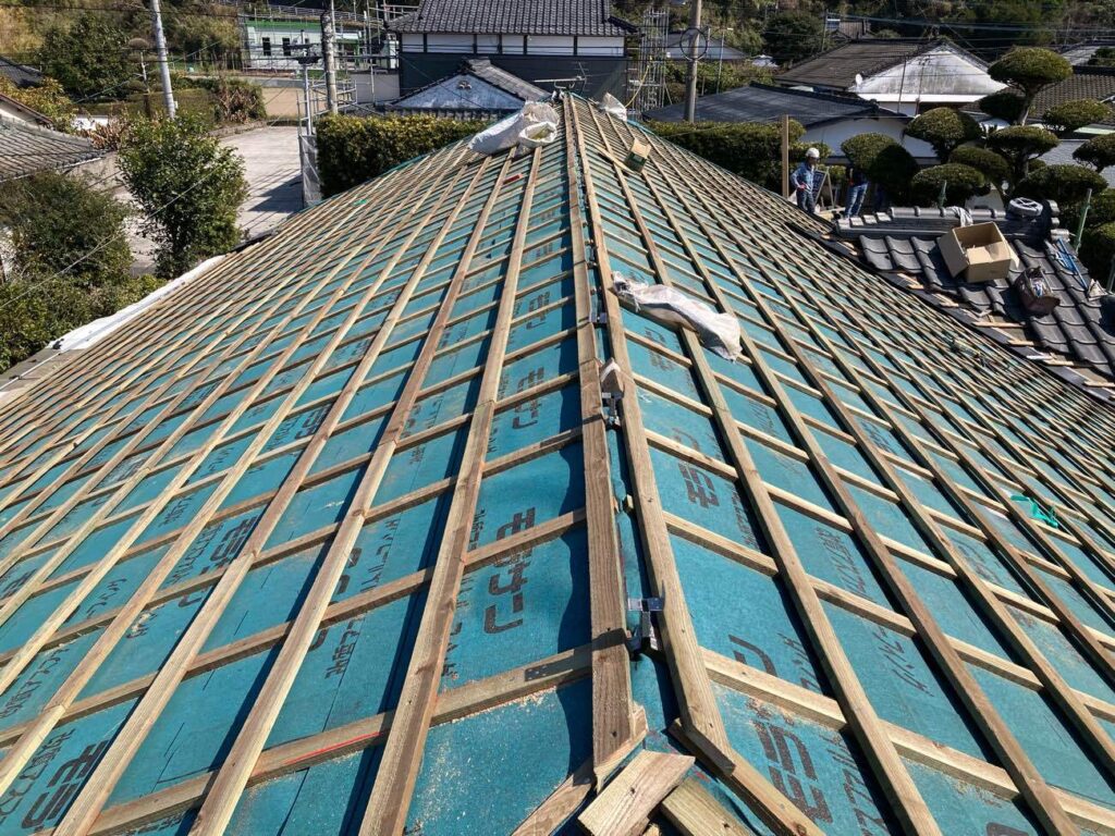 縦横に桟木を取り付け、下地施工が完了しました。過去にリフォーム済みの玄関屋根（右奥）はそのままに、作業を進めていきました。