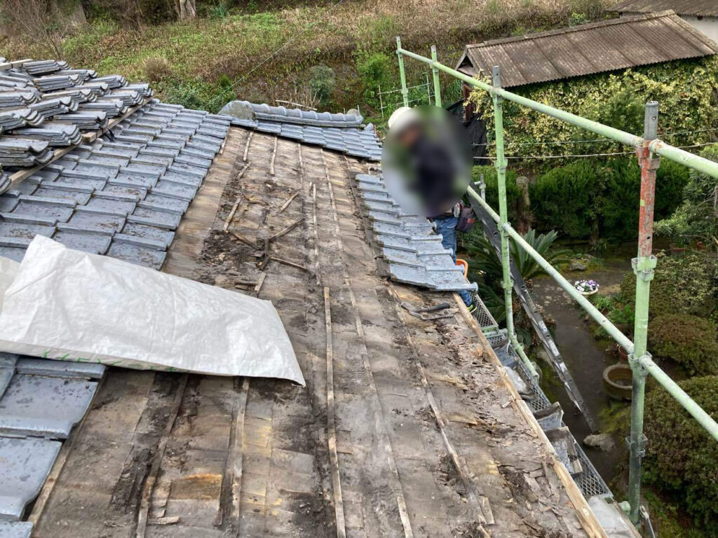 既存の瓦をいったん解体すると、長年にわたり溜まっていた火山灰や、傷んだ下地材があらわに。取り外した瓦は再利用のため、丁寧に脇へ積み重ねて保管します。 