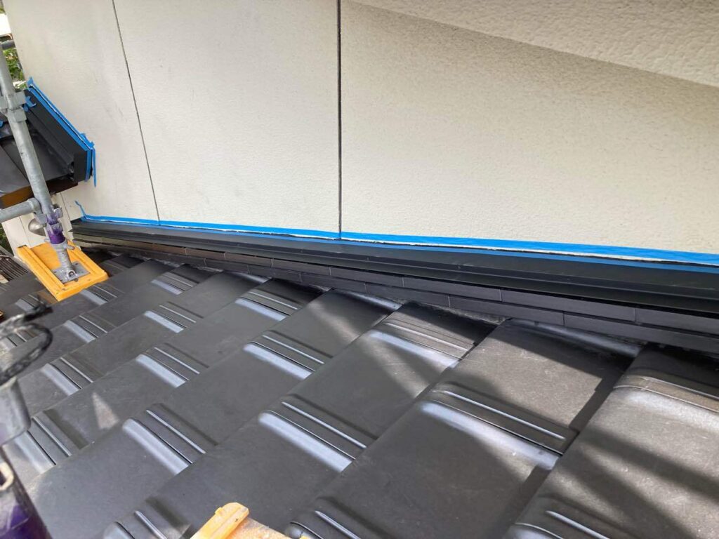 壁際は雨漏りのリスクがある難しい箇所。専用の瓦を積み、板金とシーリングでしっかりと防水処理をしました。若い職人も日々研鑽を積み、ハイレベルな施工を実現しています。