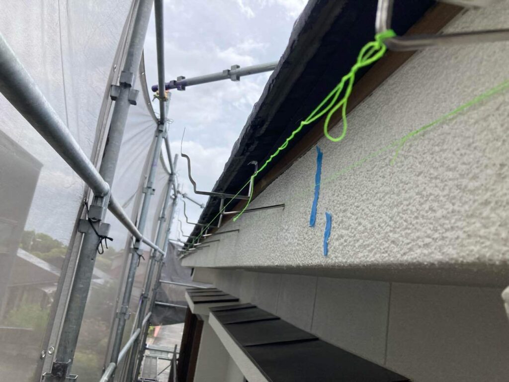 既存の雨樋を取り外したあと、糸を使用して勾配を確認しながら新しい雨樋を取り付ける準備をします。