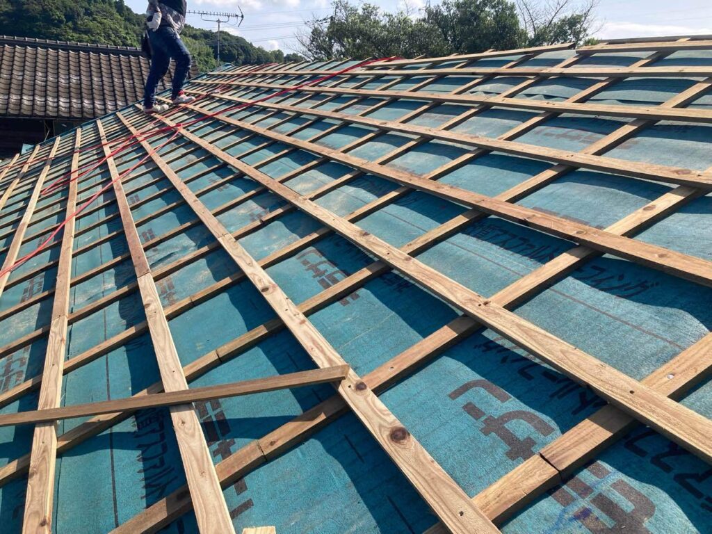 下地の野地板の状態は比較的良好であったため、上に防水シートを重ね張りして防水性を高めます。その後、瓦を固定するための角材（桟木）を縦横に取り付けました。