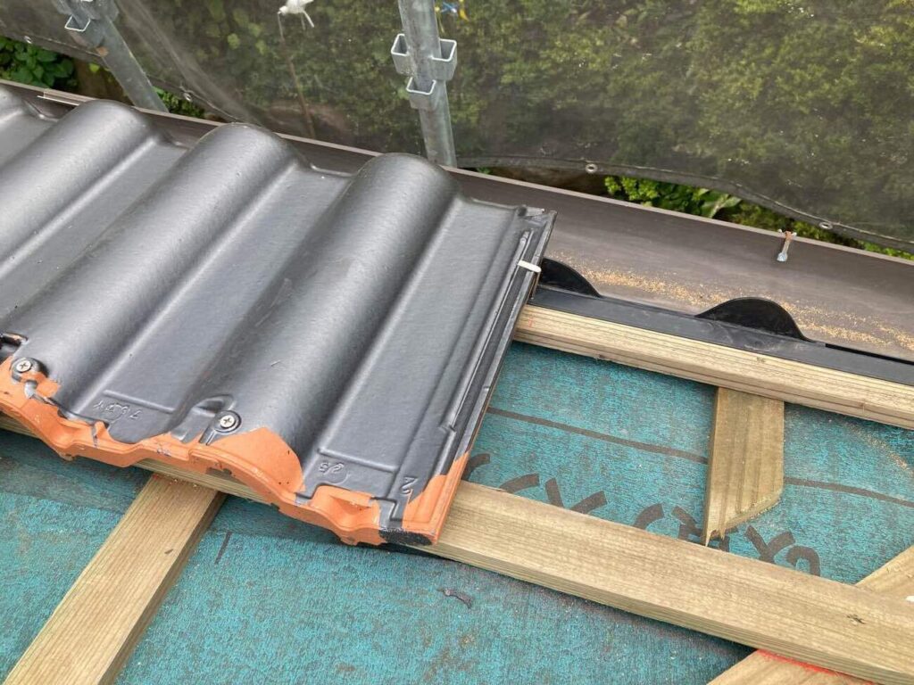 桟木に瓦をビスでしっかり固定します。屋根のすき間を通り、雨が樋へと流れるのが正しい施工といえます。